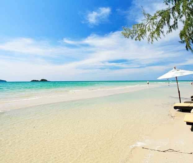 En sandstrand med klart vatten, solsängar och parasoller syns i kanten. (AI-genererad text)