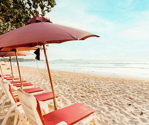 Strand med solstolar och parasoller i en rad vid havet. (AI-genererad text)