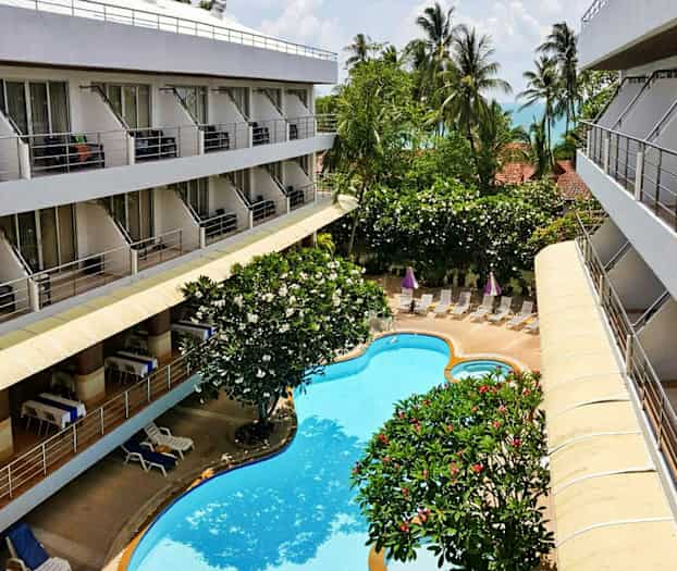 Bild av ett hotell med balkonger, trädgård och pool. (AI-genererad text)