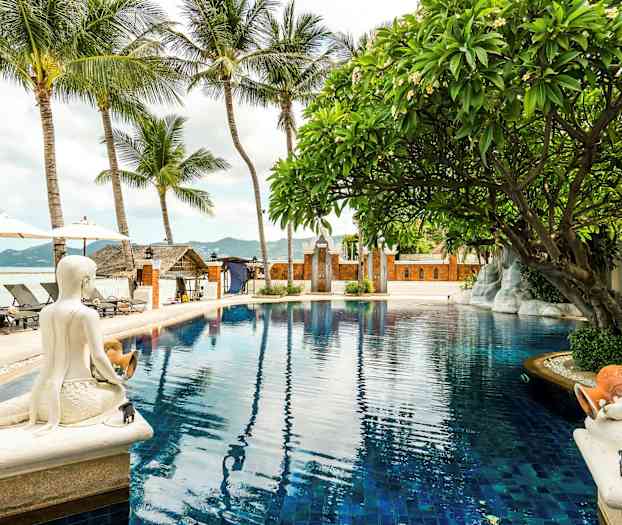 En pool omgiven av palmer, statyer och en tropisk miljö. (AI-genererad text)