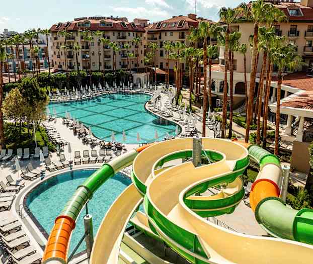 Bild av ett hotellområde med pool, solstolar och en vattenrutschbana. (AI-genererad text)
