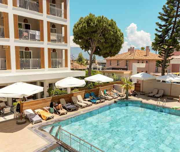 Utomhuspool framför ett hotell med solstolar och parasoller. (AI-genererad text)