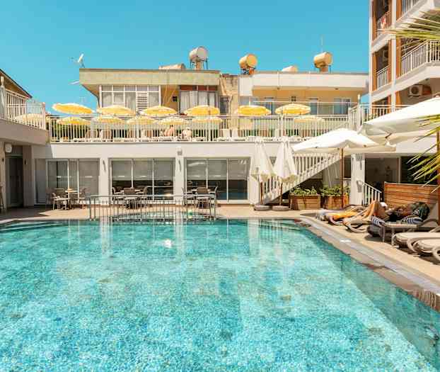 En utomhuspool omgiven av solstolar och parasoller på ett hotell. (AI-genererad text)