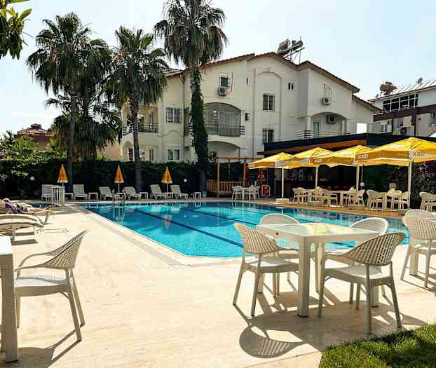 Utomhuspool vid ett hotell med solstolar och parasoller samt matplatser. (AI-genererad text)