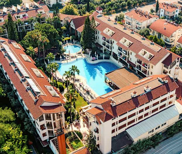 Flygbild av hotellkomplex med pool och omgivande byggnader. (AI-genererad text)