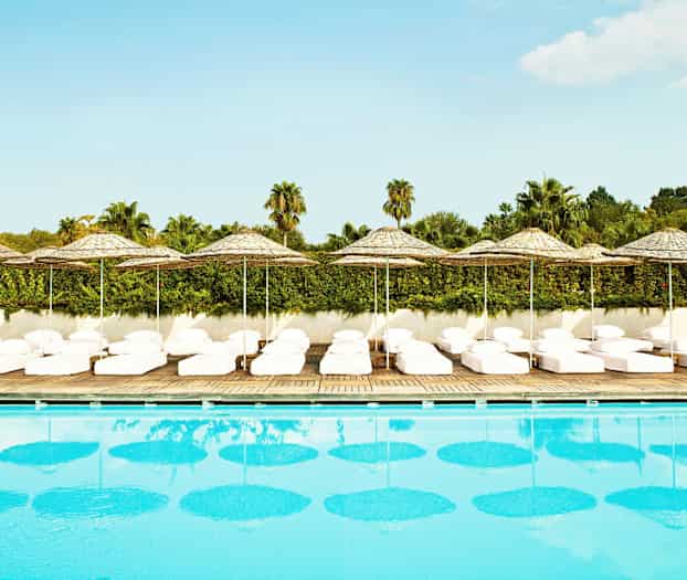 Pool med solstolar och parasoll i bakgrunden. (AI-genererad text)