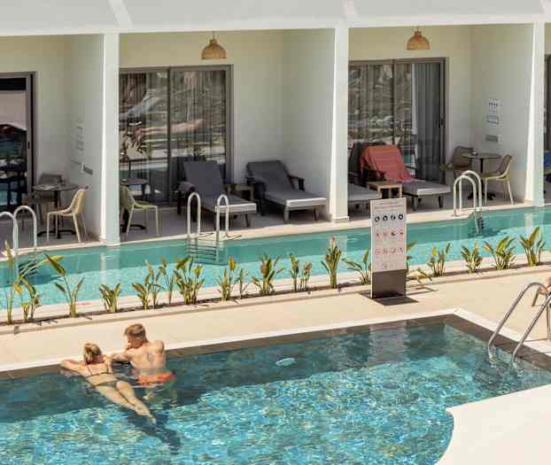 Bild som visar en pool omgiven av solstolar och rum med direkt poolaccess. (AI-genererad text)