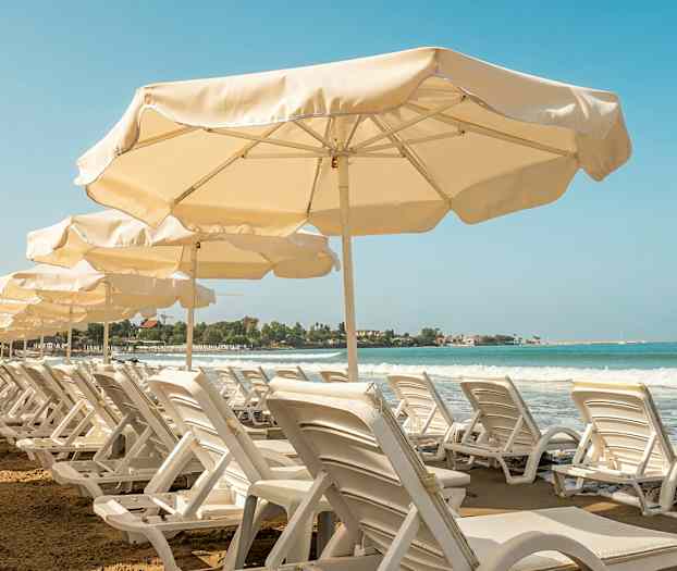 Rad av solstolar och parasoller vid en sandstrand med havsutsikt. (AI-genererad text)