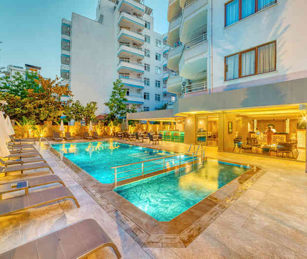 Utomhuspool med solstolar och parasoller, omgiven av byggnader. (AI-genererad text)