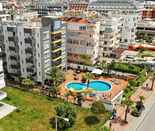 En flygbild visar ett hotellområde med en pool och omgivande byggnader. (AI-genererad text)