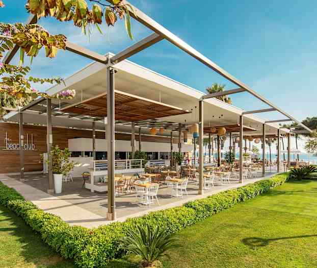 En modern utomhusrestaurang med uteservering omgiven av grönska. (AI-genererad text)