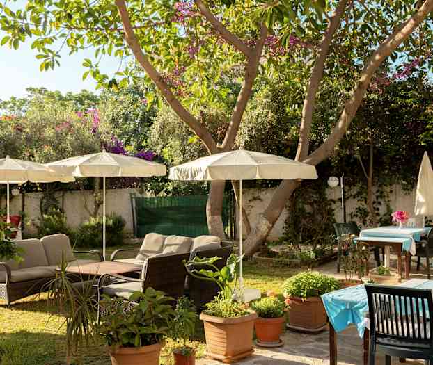 En trädgård med utemöbler och parasoller. (AI-genererad text)