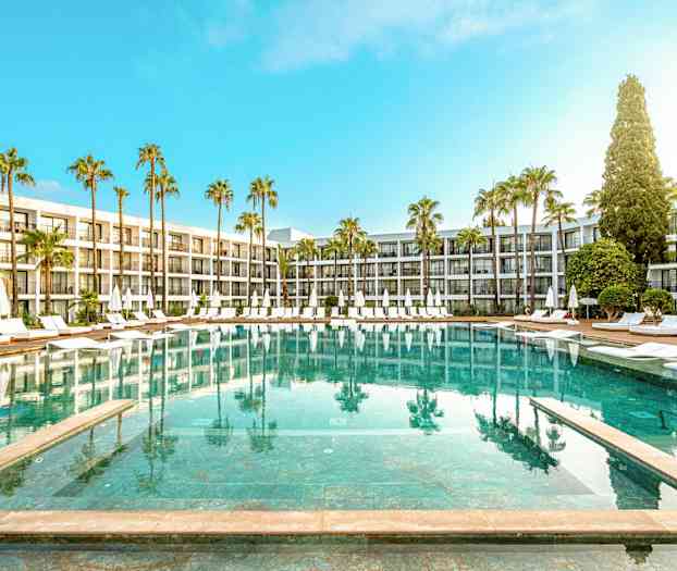 Hotellpool med solstolar och parasoller omgiven av palmträd och moderna byggnader. (AI-genererad text)