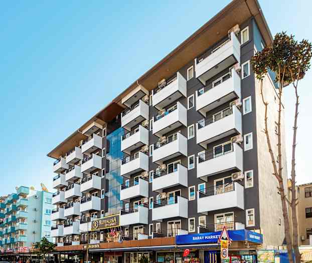 En hotellbyggnad med flera balkonger och skyltar vid ingången. (AI-genererad text)