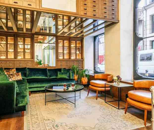 En vardagsrumsmiljö med grön soffa, två bruna fåtöljer och ett glasbord. (AI-genererad text)