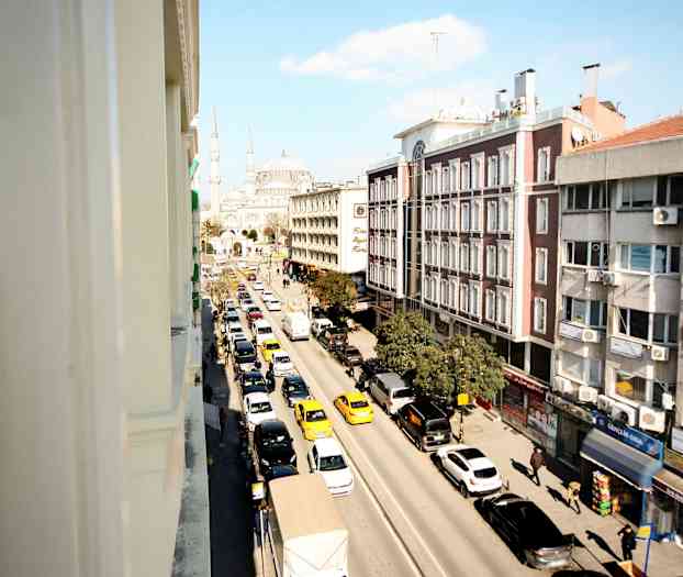 Bild av en stadsgata med trafik, byggnader längs vägen och en moské i bakgrunden. (AI-genererad text)