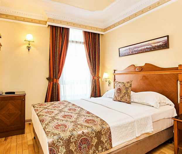 Ett hotellrum med en dubbelsäng, träinredning och dekorativa gardiner. (AI-genererad text)