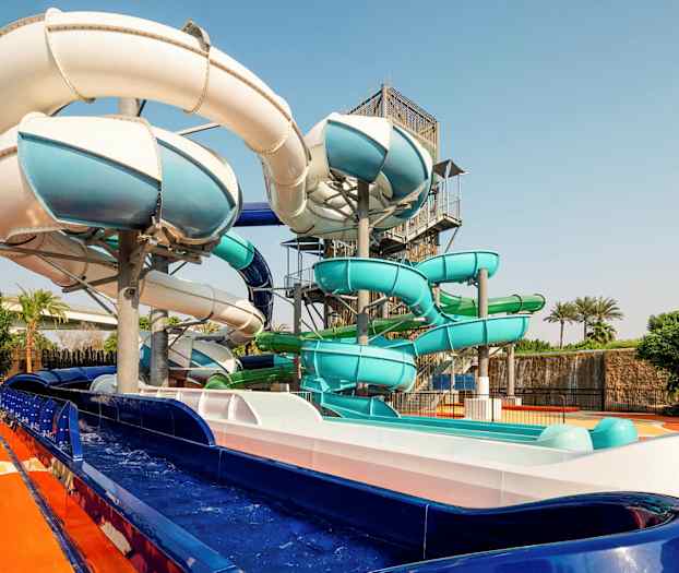 Bild av vattenrutschbanor i olika färger på en utomhusanläggning. (AI-genererad text)