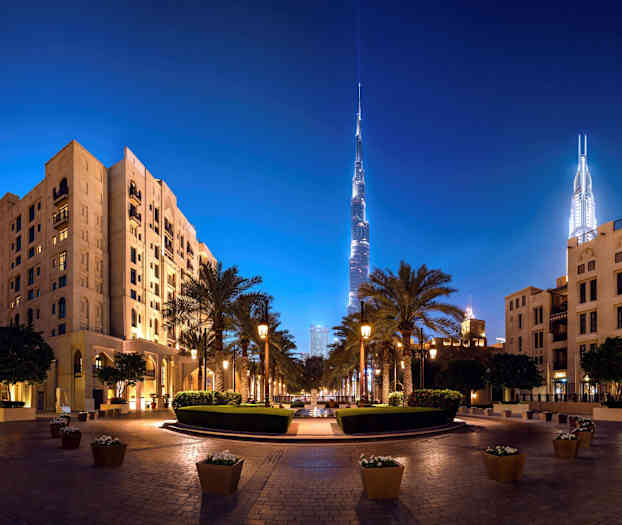 Nattbild av en stadsmiljö med höga byggnader och palmer. (AI-genererad text)