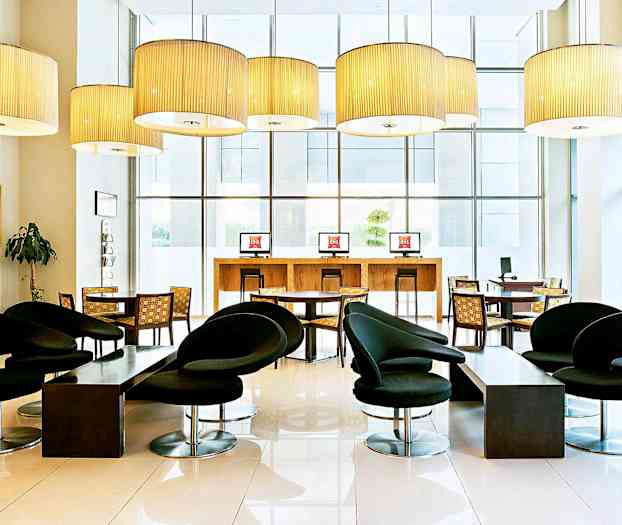 Ett modernt möblerat hotellobbyn med svarta stolar, bord och datorstationer. (AI-genererad text)