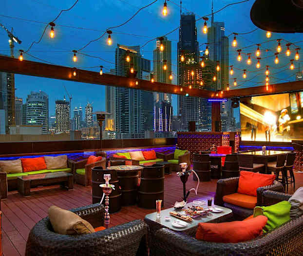 En takterrass med sittgrupper, dekorativa lampor och utsikt över en stadssilhuett på kvällen. (AI-genererad text)