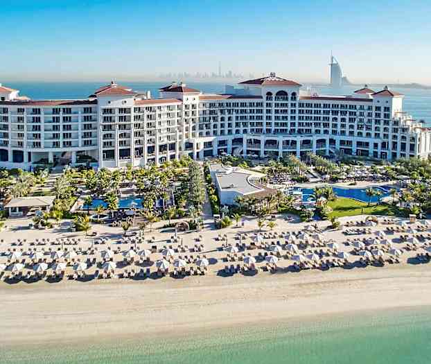 En stor semesterort med pooler, solsängar och en vit sandstrand vid havet. (AI-genererad text)