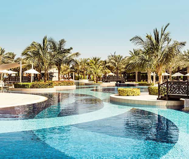 En resortpool med palmer och sittplatser i bakgrunden. (AI-genererad text)