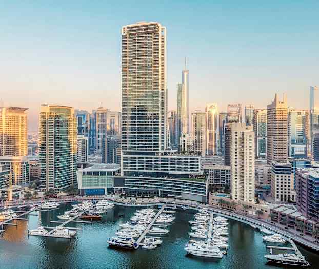 Vy över en marina med båtar och höghus i bakgrunden. (AI-genererad text)