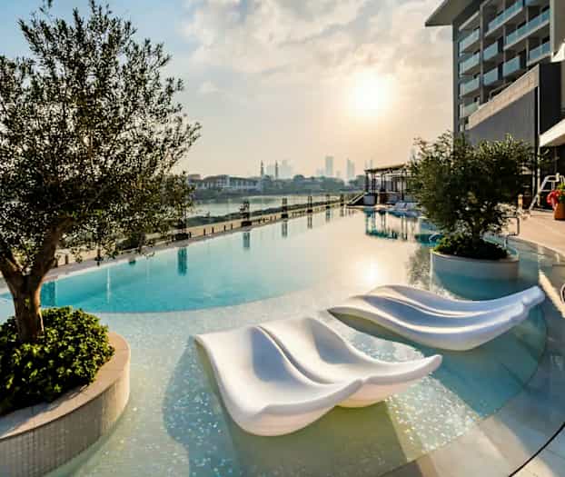 Bild av en infinitypool vid solnedgången med moderna solsängar och omgivande grönska. (AI-genererad text)