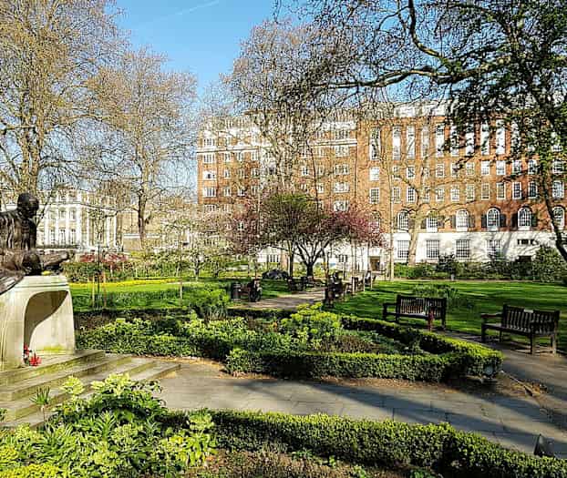 Staty i en park med grönska och bänkar. (AI-genererad text)