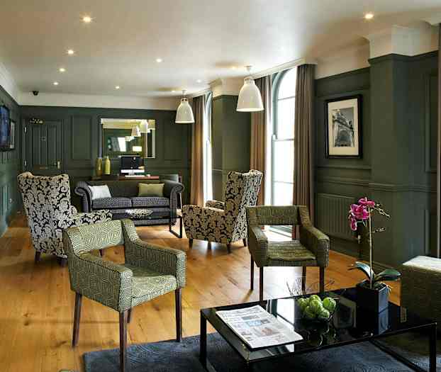 Ett elegant hotelloungeområde med fåtöljer och soffor, prydnadsväxter och modern inredning. (AI-genererad text)