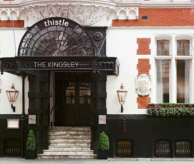 Hotellingång med trappor, skylt och blommor. (AI-genererad text)