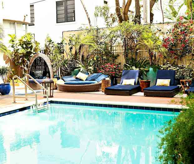 En utomhuspool med omgivande solstolar och grönska. (AI-genererad text)