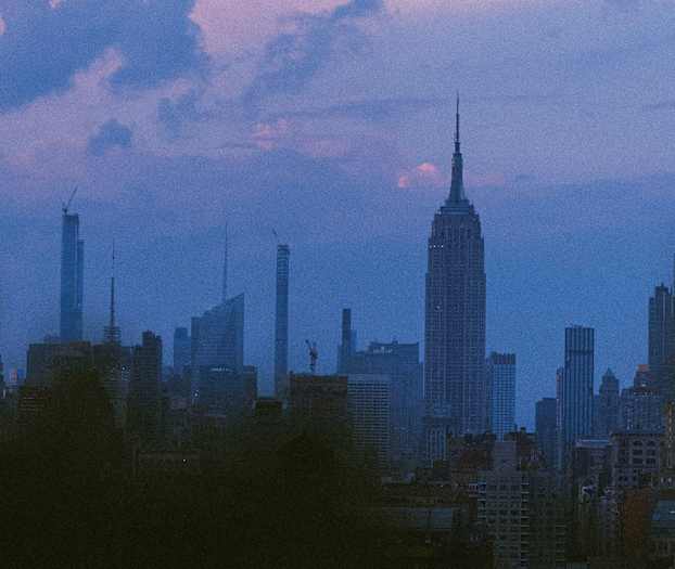 Utsikt över en stadssilhuett under en skymning med flera skyskrapor mot en färggrann himmel. (AI-genererad text)