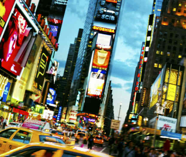 Trafikerad gata med taxibilar och reklamklädda byggnader i en stadsmiljö. (AI-genererad text)