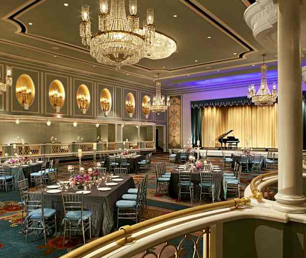 Elegant balsal dekorerad med ljuskronor, dukade bord och en scen med en flygel. (AI-genererad text)