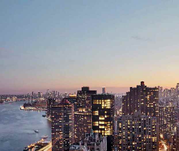 Vy över en stad med flera höghus och en flod i förgrunden vid solnedgången. (AI-genererad text)