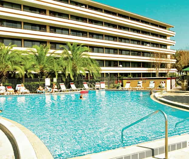 Bild av en utomhuspool framför ett flervåningshotell. (AI-genererad text)