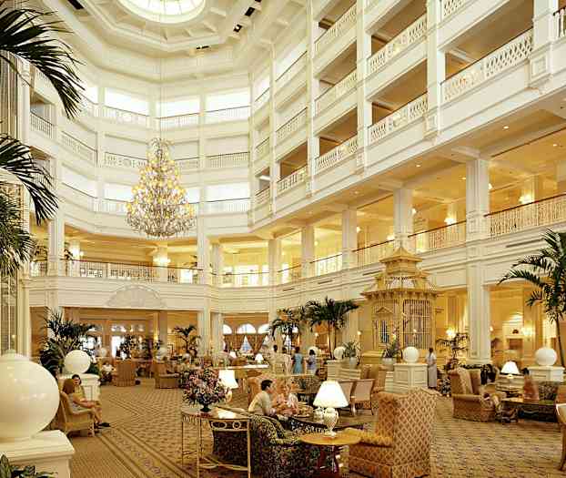 En stor och elegant hotellobby med högt i tak, en praktfull ljuskrona, bekväma sittplatser och växter som dekoration. (AI-genererad text)