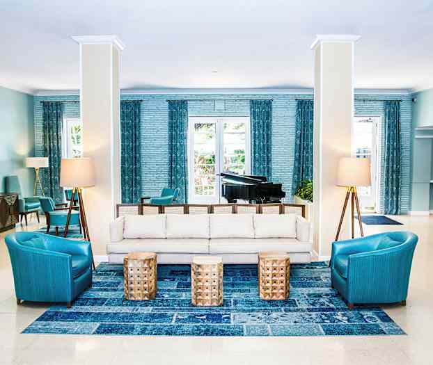 Interiörbild av en hotellobby med sittgrupp, soffor, fåtöljer och bord, samt en flygel i bakgrunden. (AI-genererad text)