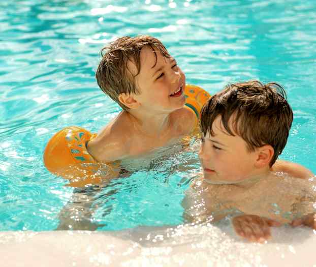 Två barn leker i en swimmingpool fylld med klart vatten. (AI-genererad text)