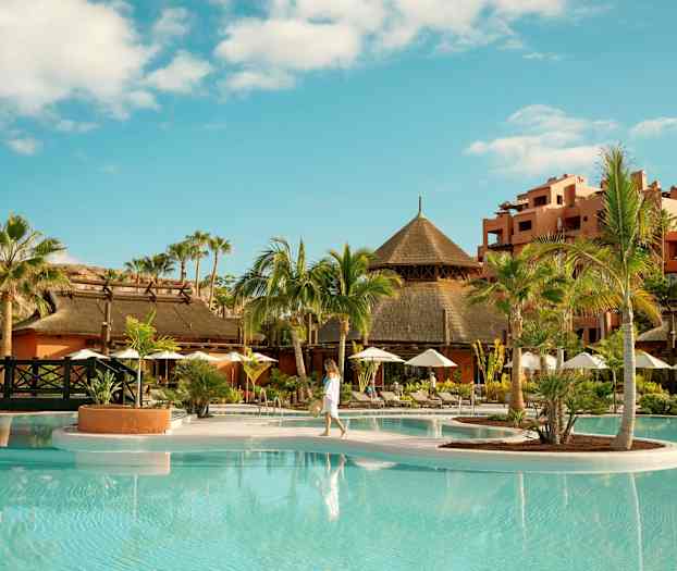 Tropisk resort med palmer, pool och traditionella byggnader. (AI-genererad text)