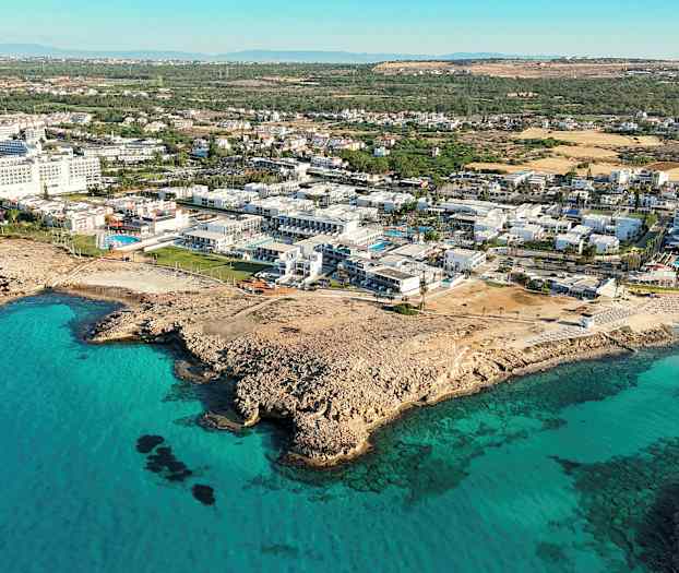 Flygfoto över kuststad med hotell och blått hav. (AI-genererad text)