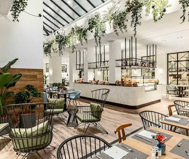 Modern restaurang med eleganta möbler och gröna växter. (AI-genererad text)