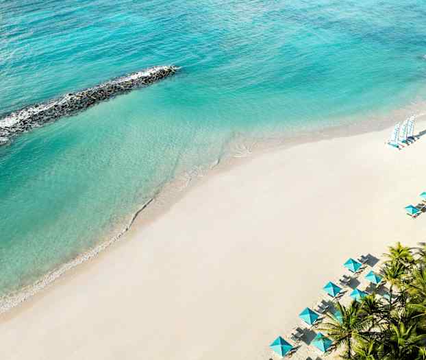 En sandstrand med turkost hav och parasoll. (AI-genererad text)