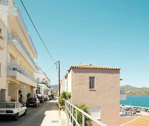 En gata med parkering och flervåningshus vid havet. (AI-genererad text)