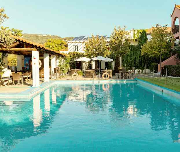 Poolområde med omgivande byggnader och grönska. (AI-genererad text)