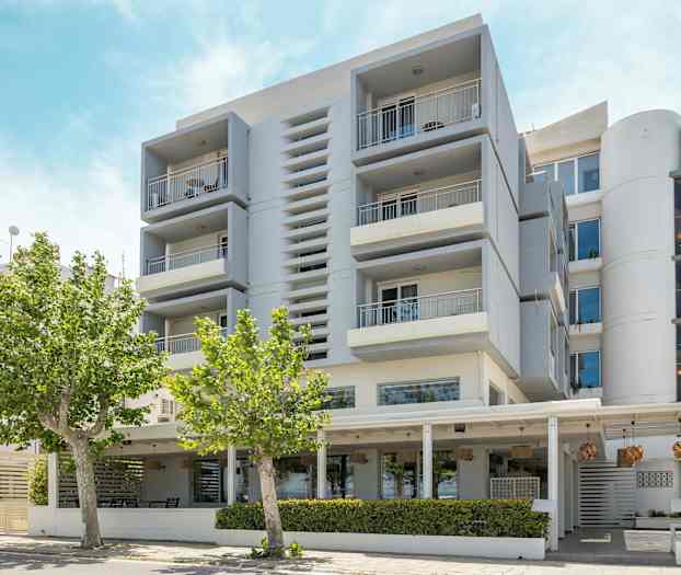 Modern byggnad med balkonger och träd i förgrunden. (AI-genererad text)