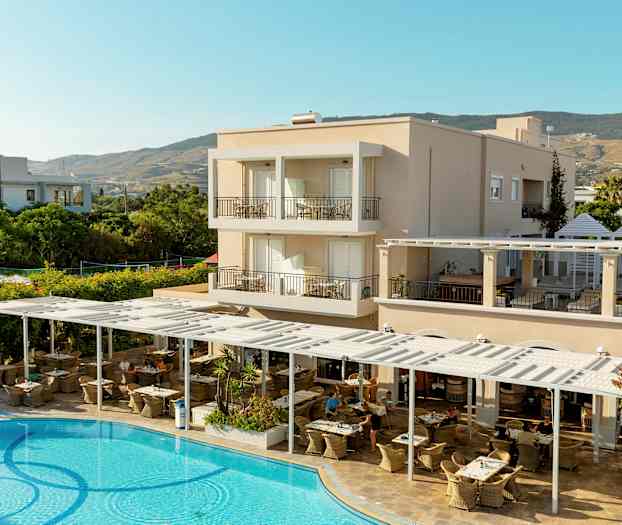 En hotellbyggnad med balkonger, en utomhusrestaurang och en pool i förgrunden. (AI-genererad text)