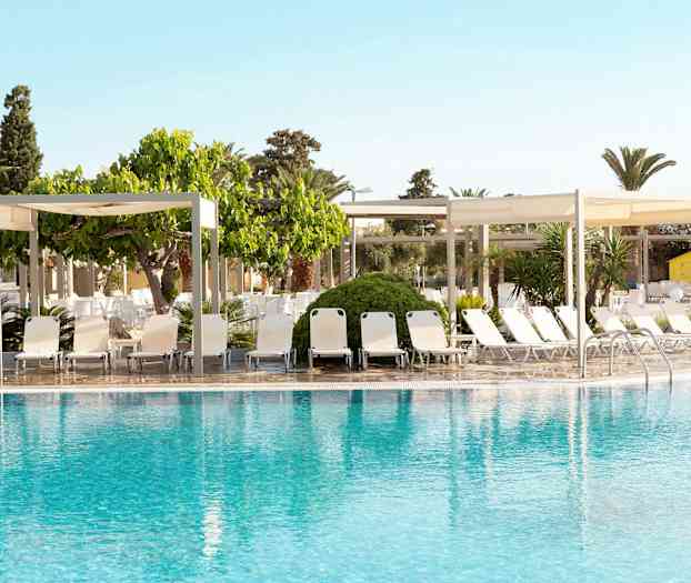 En pool med solstolar och skuggande paviljonger i bakgrunden. (AI-genererad text)